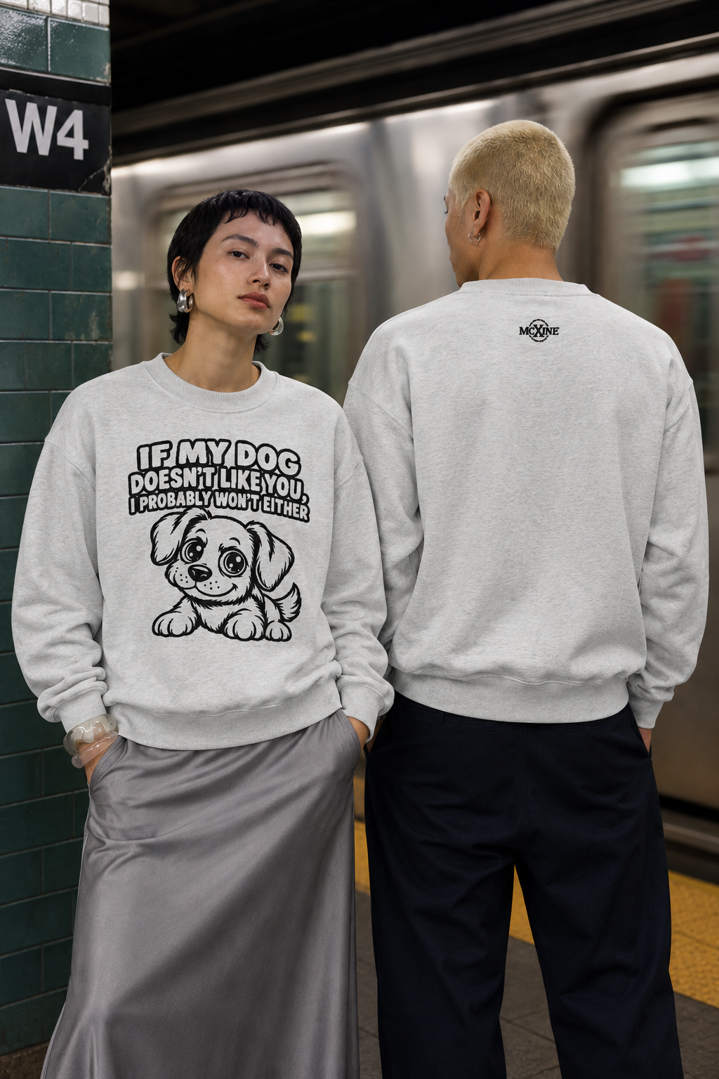 Two people in light grey knitted jumpers at a metro station, back view with MC X INE logo
