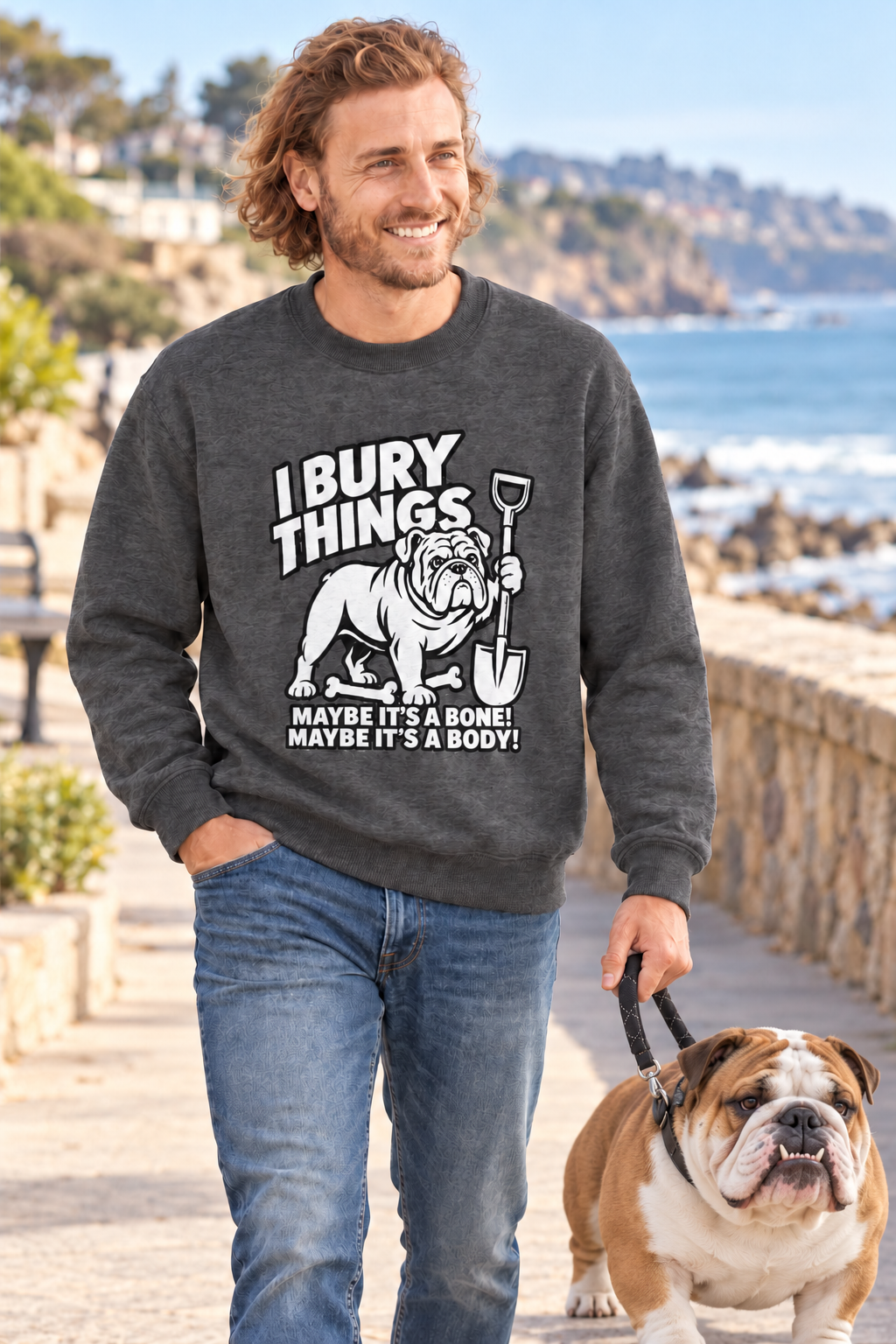 Man and English bulldog by the sea, he wears the I Bury Things bulldog jumper