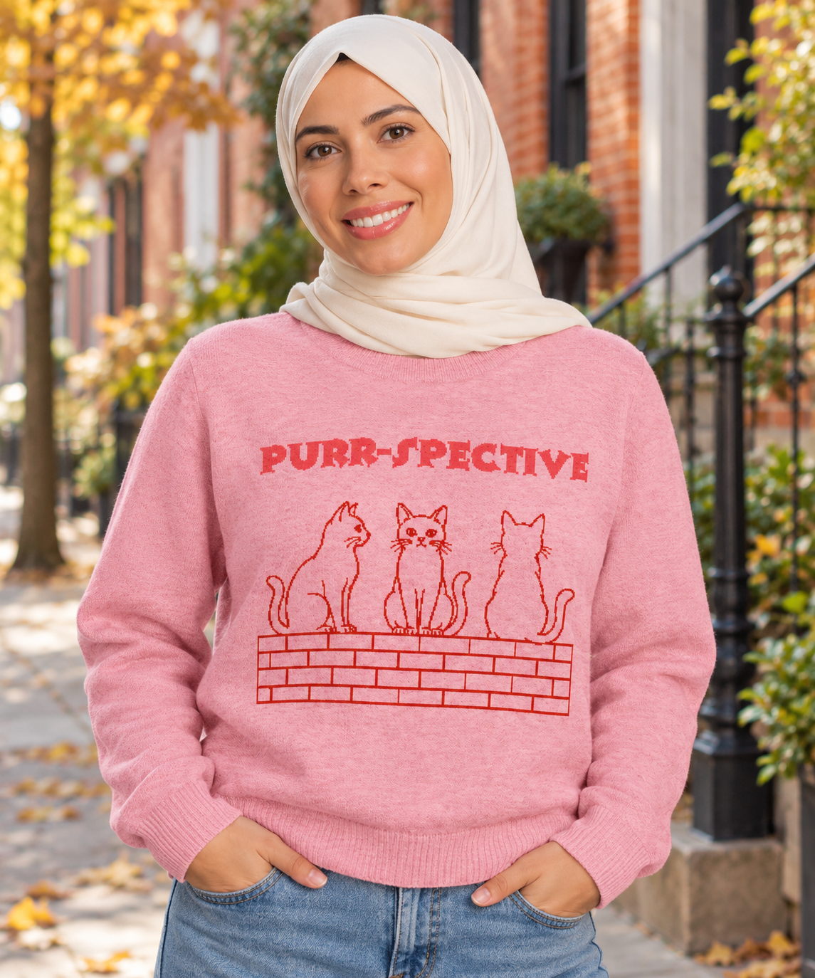 Woman in the pink Purr-spective cat jumper smiling at a grey tabby cat